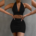 Black halter dress featuring bodycon fit and pleated skirt, captured from the side, elegant fashion choice.