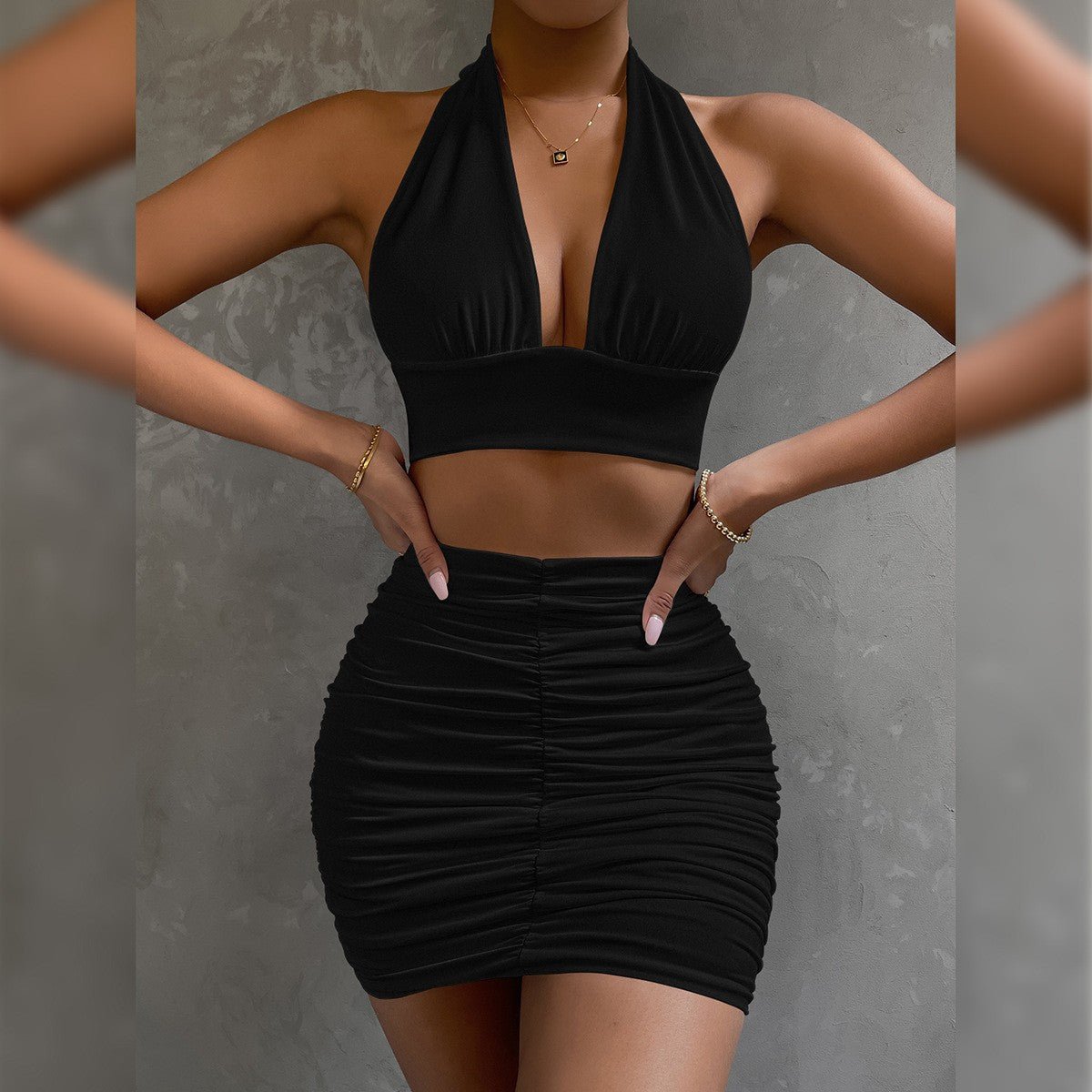 Black halter dress featuring bodycon fit and pleated skirt, captured from the side, elegant fashion choice.