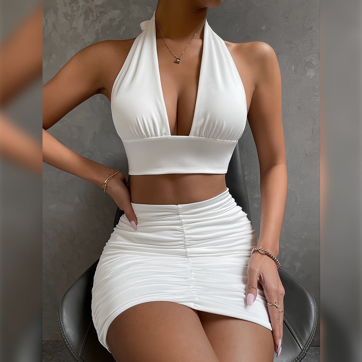 Side view of a white halter dress with bodycon fit and pleated skirt, perfect for a chic capsule wardrobe.