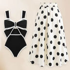 Bikini and skirt set in black and white with polka dots and bow detail, solid background.