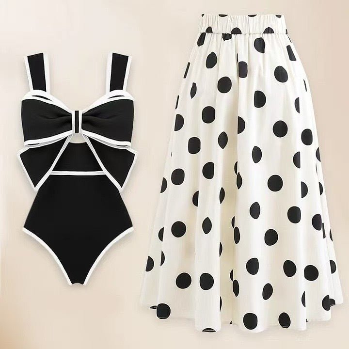 Bikini and skirt set in black and white with polka dots and bow detail, solid background.