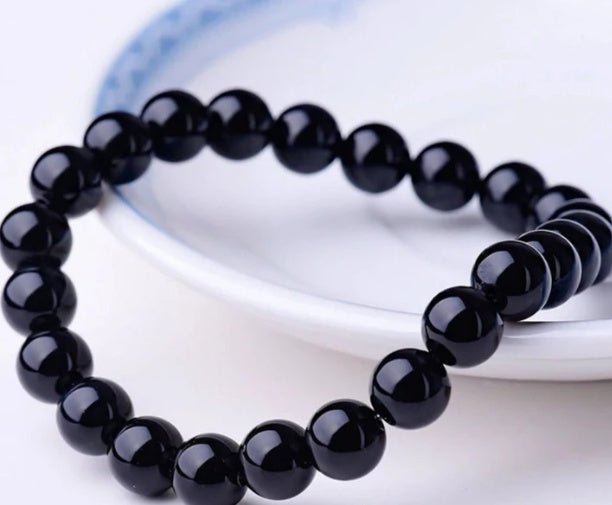 Close-up of black onyx bracelet with round beads, showcasing 21 cm length