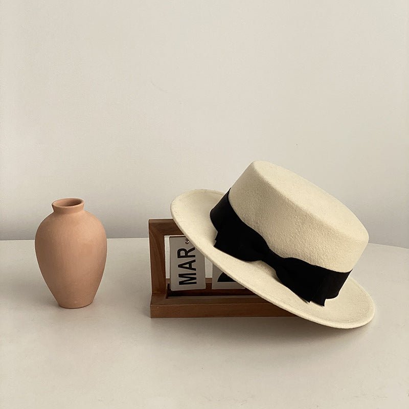 Black bow flat-brimmed cap displayed in a natural setting, showcasing its elegant style and flat brim.
