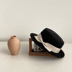 Khaki bow flat-brimmed cap against a natural background, emphasizing its stylish design and flat brim.