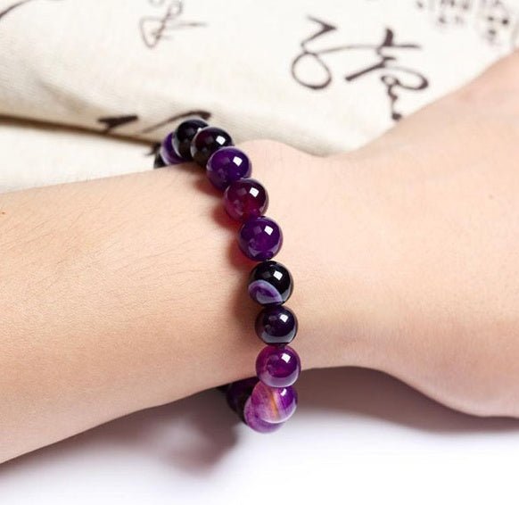 Lifestyle shot of Violet Agate Bracelet worn on wrist, displaying smooth beads in a natural setting.