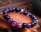 Lifestyle shot of Violet Agate Bracelet worn on wrist, featuring smooth beads in a natural setting.