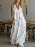 Lifestyle shot of a white sleeveless v-neck long dress featuring front pockets, perfect for casual summer outings.
