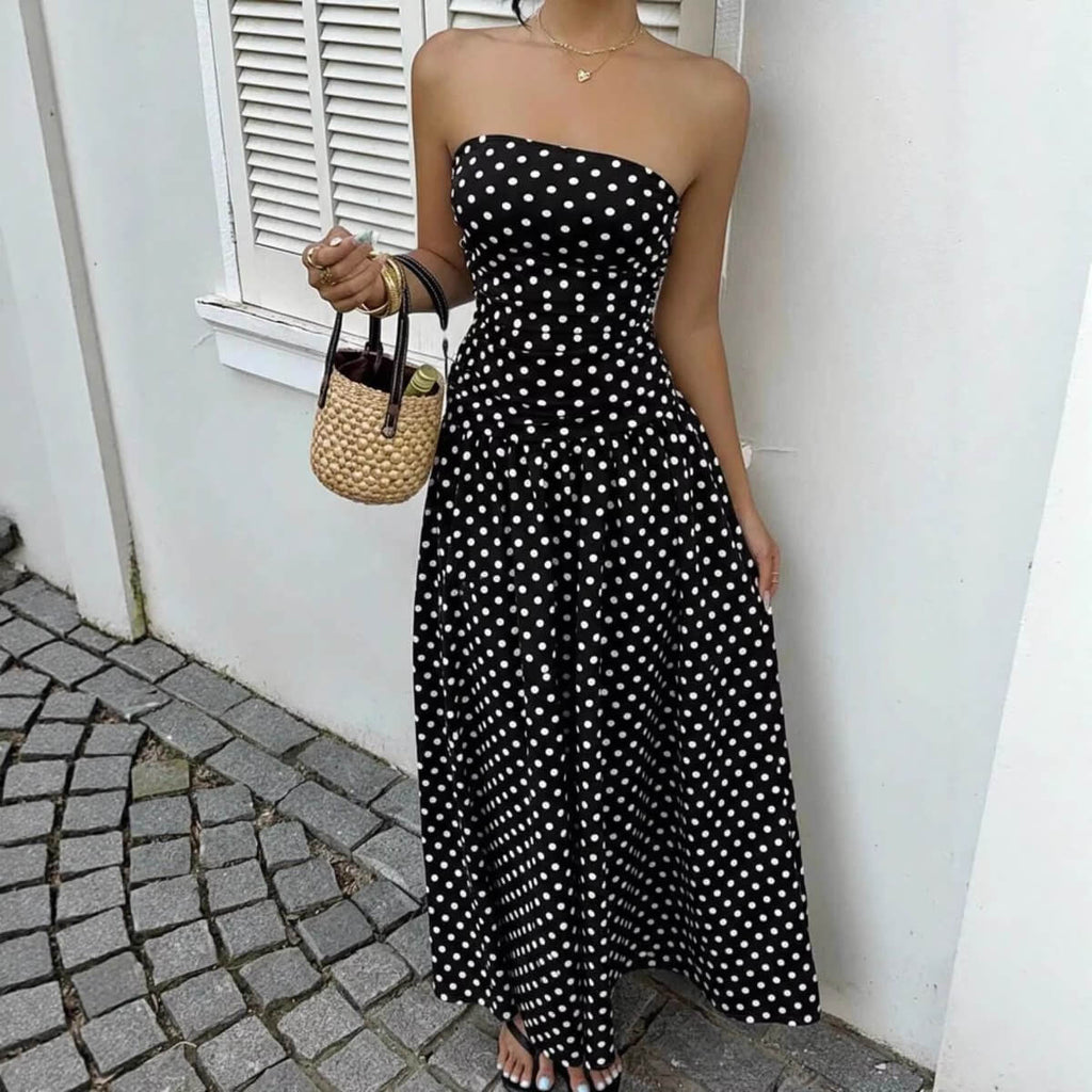 Chic black off-shoulder dress with strapless design and flowy skirt in lifestyle shot.