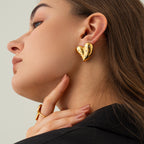 Detail shot of gold heart earrings with decorative elements, showcasing the heart shape.