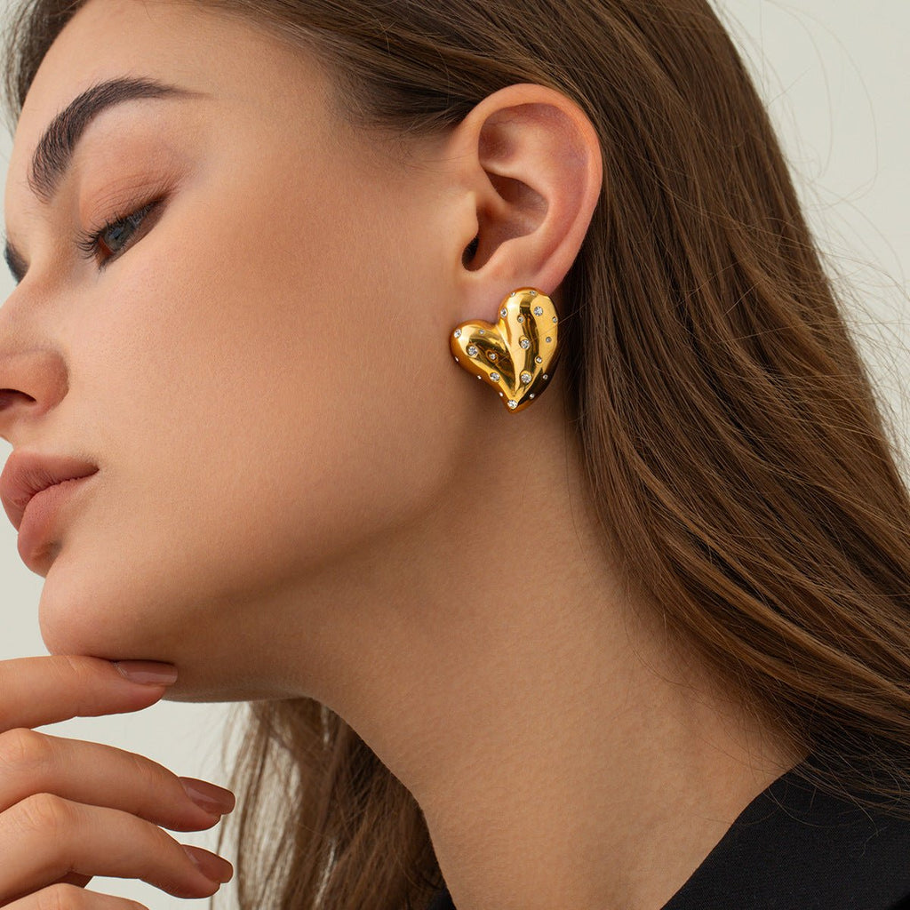 Lifestyle shot of a woman wearing gold heart earrings, showcasing the elegant heart shape.
