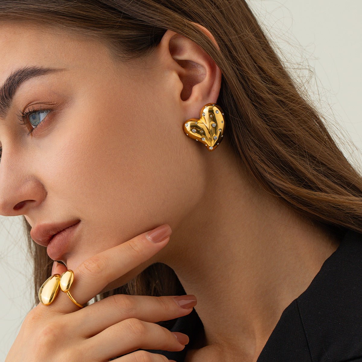 Gold heart earrings in solid color background, lifestyle shot capturing heart shape and stainless steel.