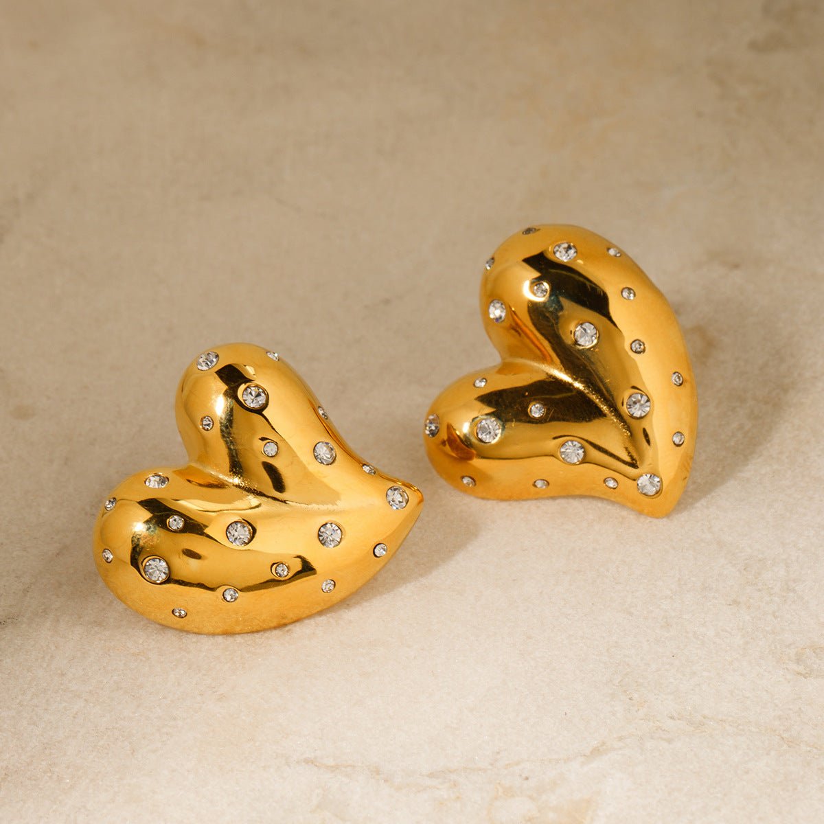 Gold heart earrings in solid color background, lifestyle shot featuring diamond accents.