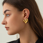 Gold heart earrings in solid color background, lifestyle shot emphasizing the elegant design.