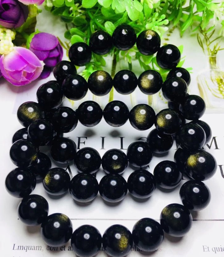 Close-up detail of Gold Sapphire Bracelet featuring round beads, highlighting black and gold colors on a white background.