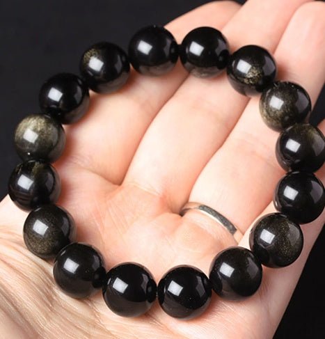 Detail shot of Black gemstone Gold Sapphire Bracelet with round beads, showcasing black and gold on a black background.