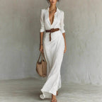 Lifestyle shot of a white long dress featuring a belted waist and button lapel, ideal for a capsule wardrobe.
