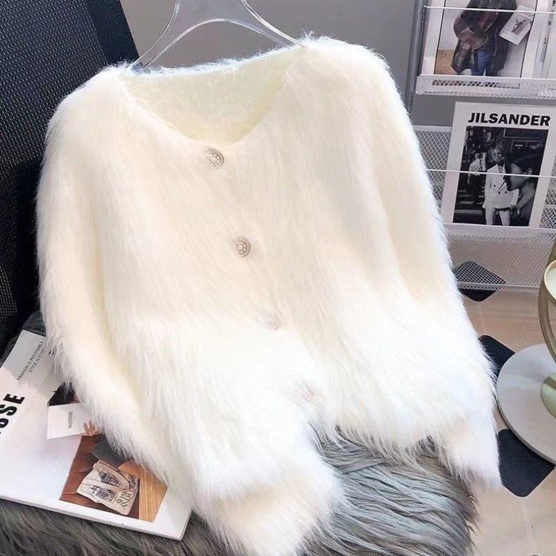Close-up detail of a white knitted cardigan featuring button closure and fluffy texture.