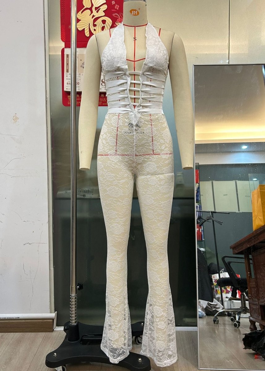 Front view of a white lace-up jumpsuit highlighting its see-through features and deep V-neck.