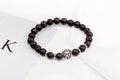 Detail close-up of black stone bracelet with lion head charm, showcasing silver accents on white background