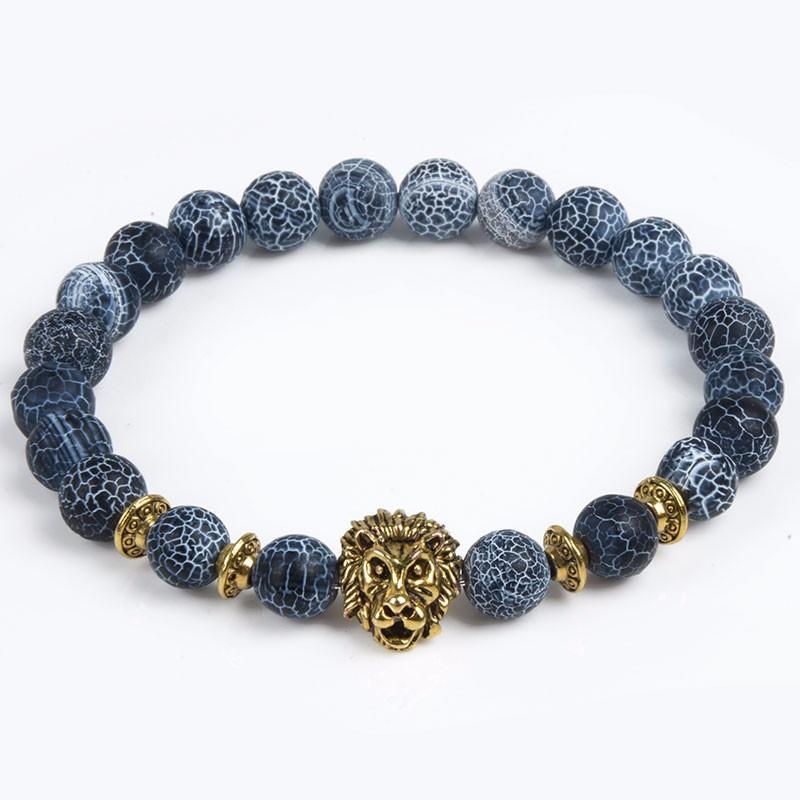 Detail close-up of blue stone bracelet with lion charm, featuring gold accents on white background