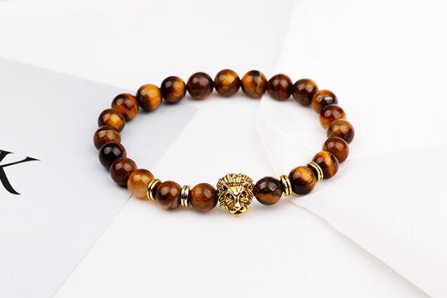 Detail close-up of brown stone bracelet with lion charm, highlighting beaded design on white background