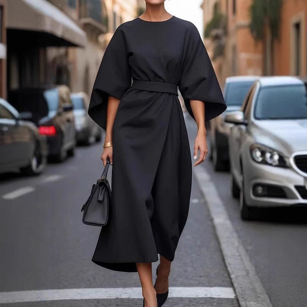 Lifestyle shot of a black batwing sleeve dress with waist tie, elegant minimalist style.