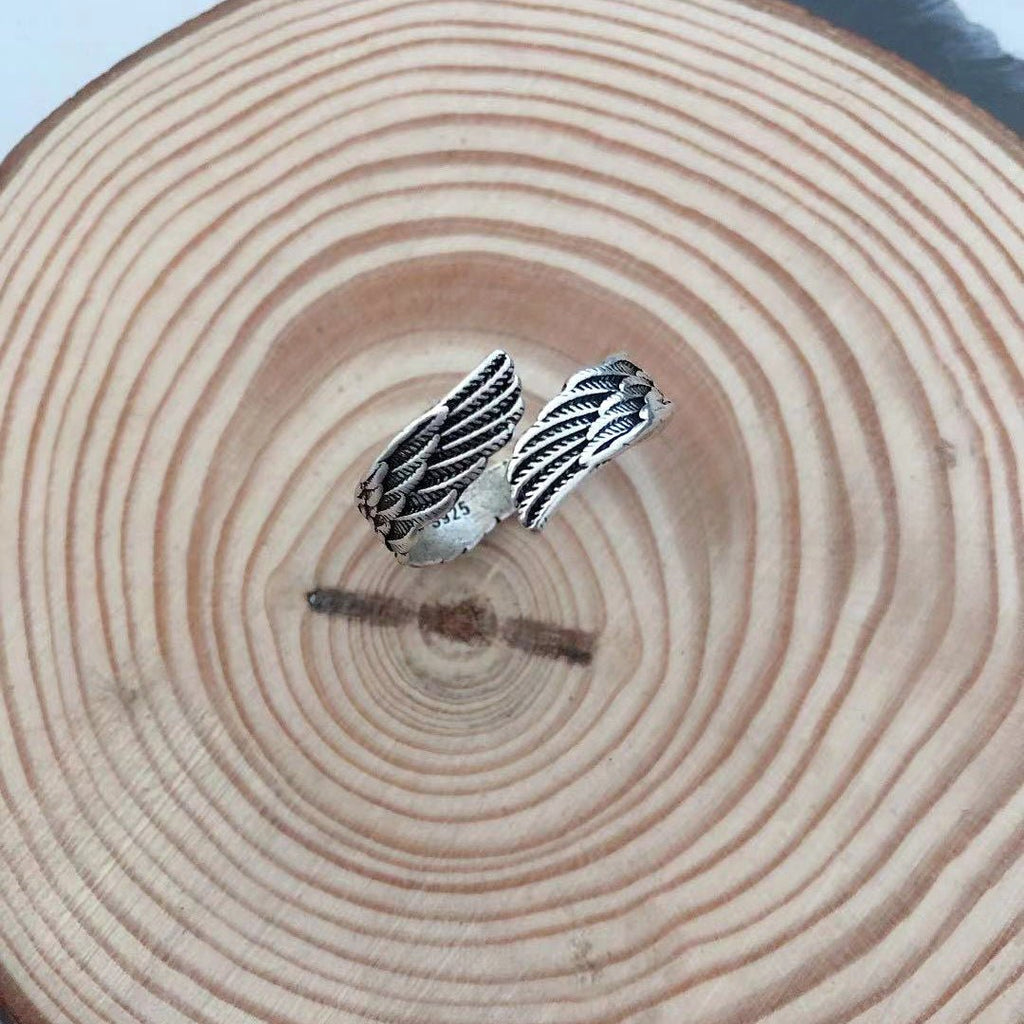 Detail shot of the silver couple ring highlighting the angel wings design in a natural setting.