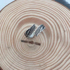 Detail shot of the silver couple ring highlighting the angel wings design in a natural setting.