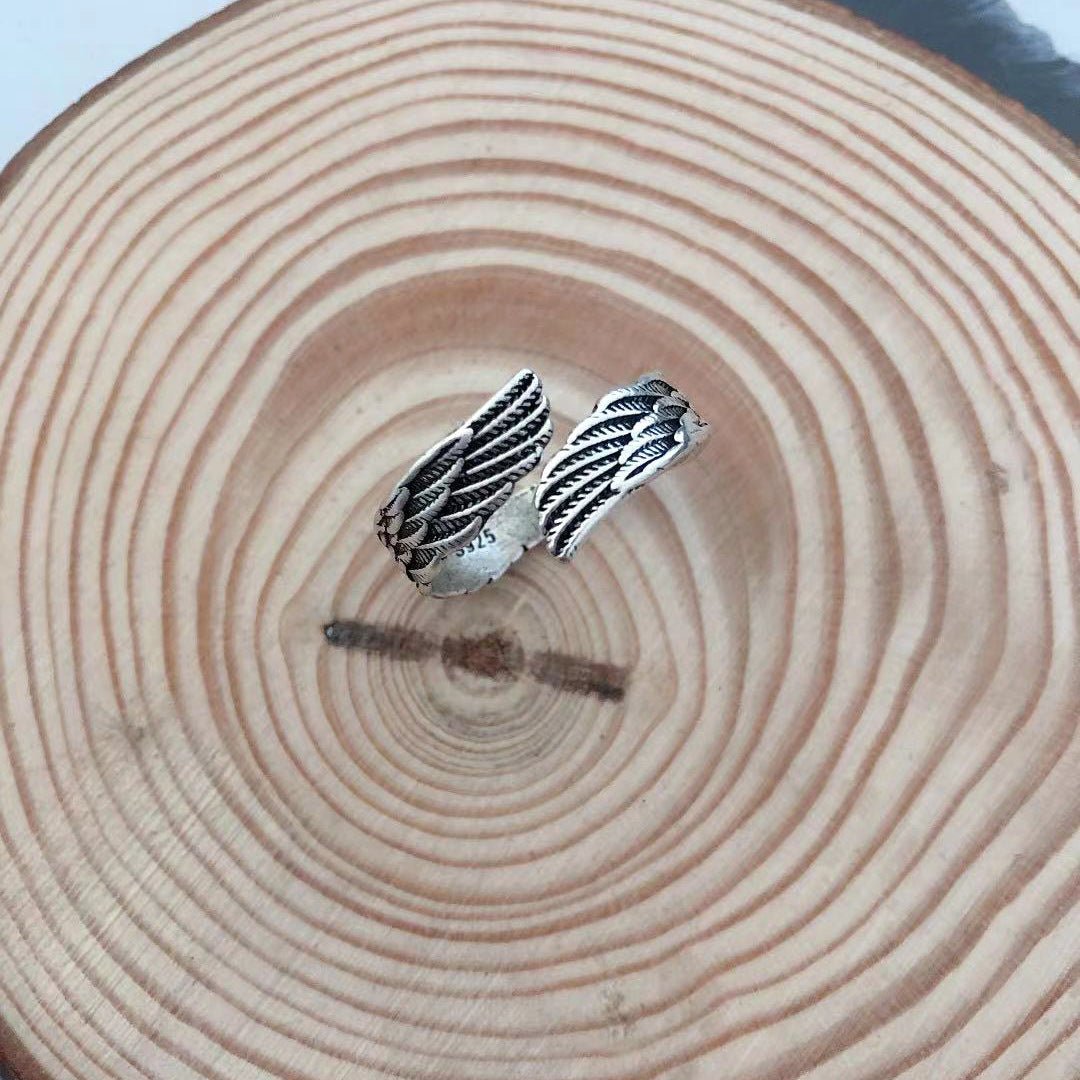 Detail shot of the silver couple ring highlighting the angel wings design in a natural setting.