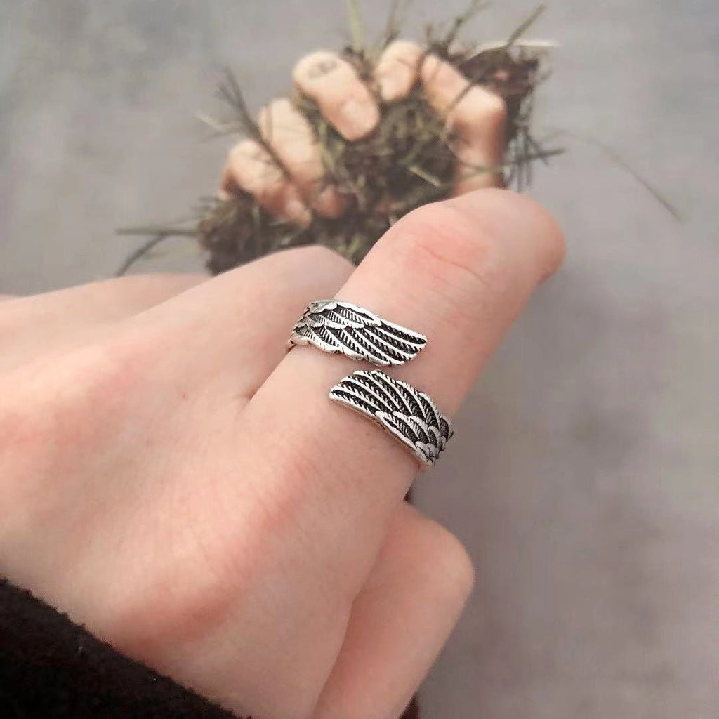 Silver couple ring with angel wings design displayed in a natural setting, emphasizing its elegant style.