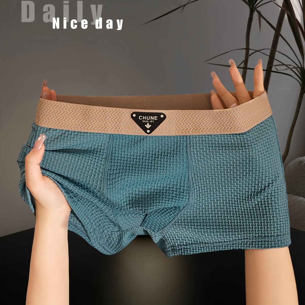 Detail shot of teal boxer briefs with soft fabric and elastic waistband, displayed in a studio environment.