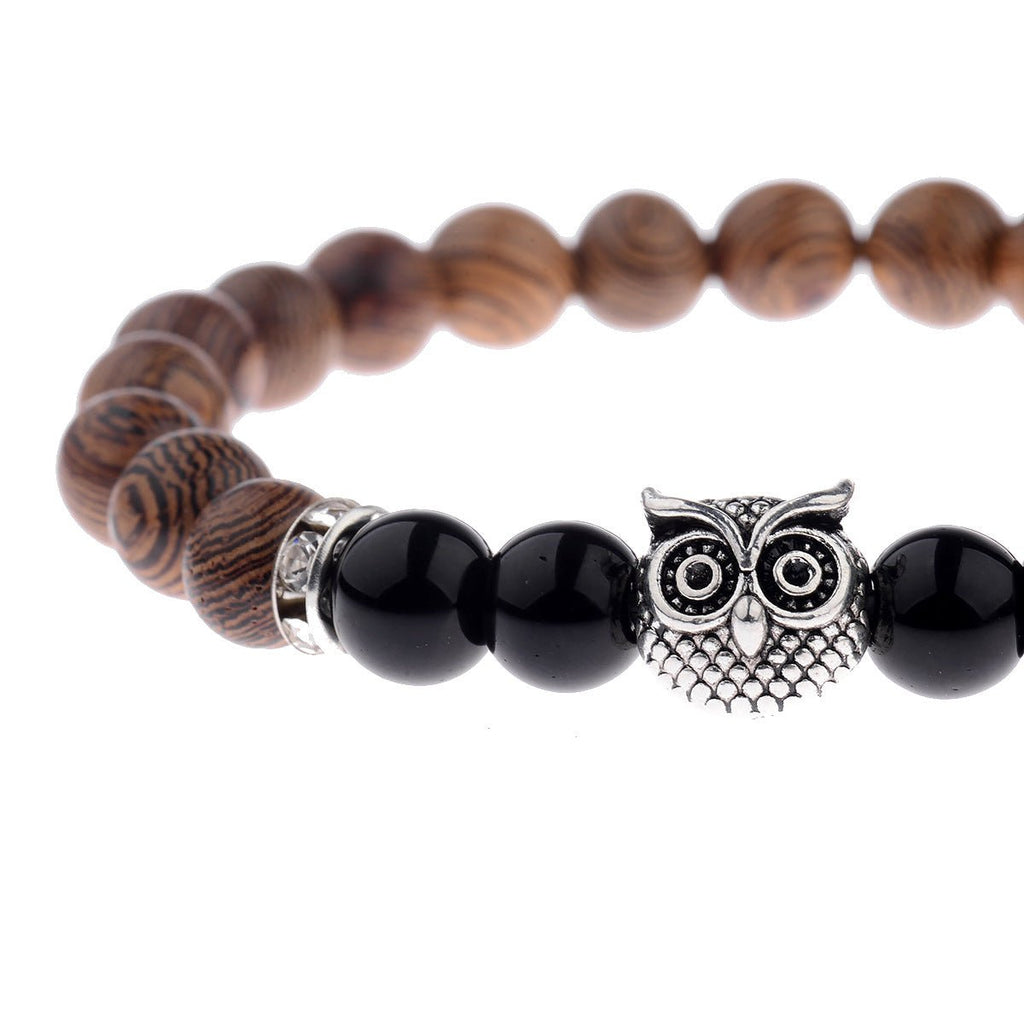 Detail close-up of the exotic wood grain bracelet with an owl charm on a white background, emphasizing chic fashion.