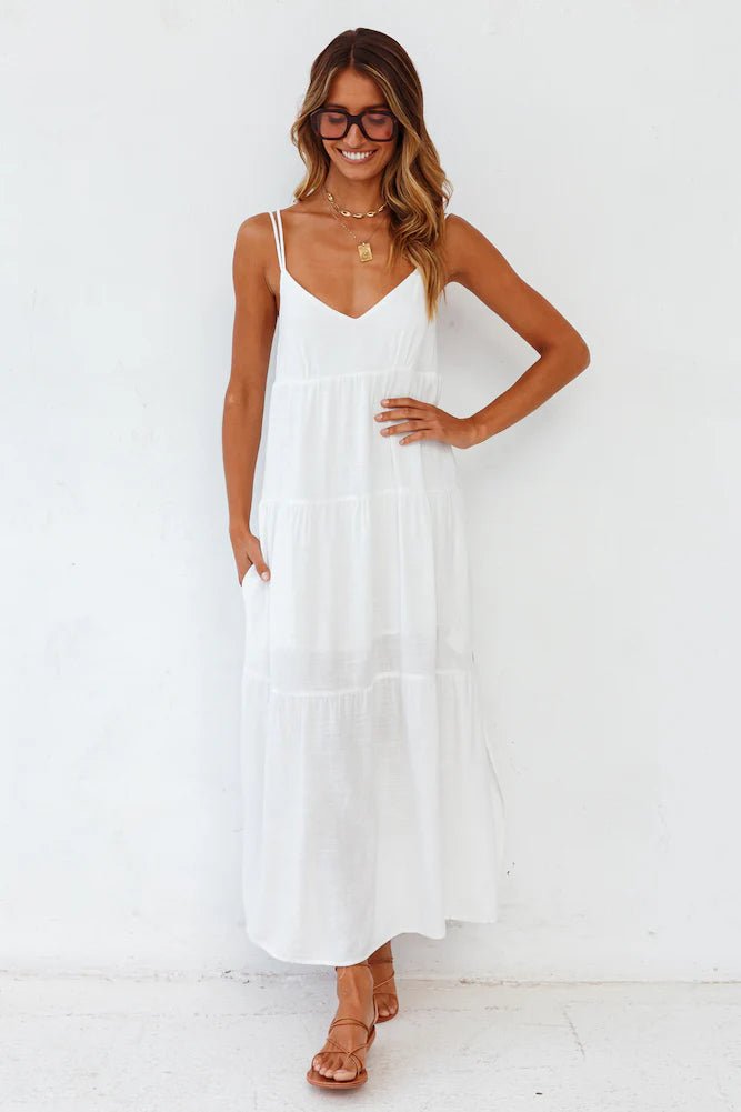 Elegant white maxi dress featuring spaghetti straps and flowy design, captured in a natural environment.