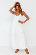 Lifestyle shot of a white maxi dress with spaghetti straps and flowy design, set against a solid backdrop.