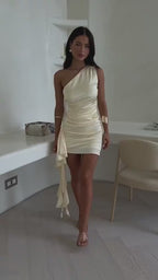 Lifestyle video featuring a cream one-shoulder mini dress, sleeveless, emphasizing elegant design.