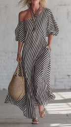 Lifestyle shot of a gray and beige striped off-shoulder maxi dress, flowy fabric in a natural setting.