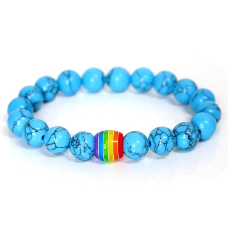 Detail close-up of the blue rainbow bead bracelet featuring an elastic band and colorful beads on a white background