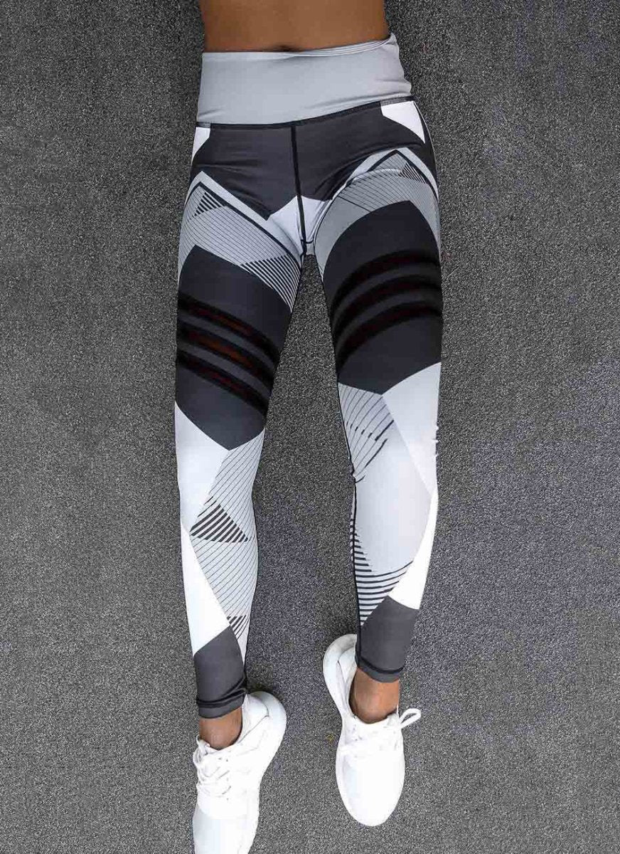 Detail view of gray and black reflective sport yoga pants, showcasing mesh panels and elastic waistband.