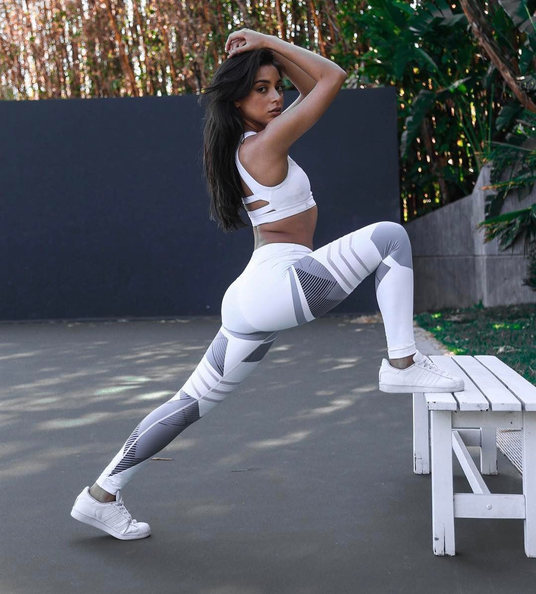 Lifestyle shot of reflective sport yoga pants in white and gray, featuring high waist and stretch fabric.