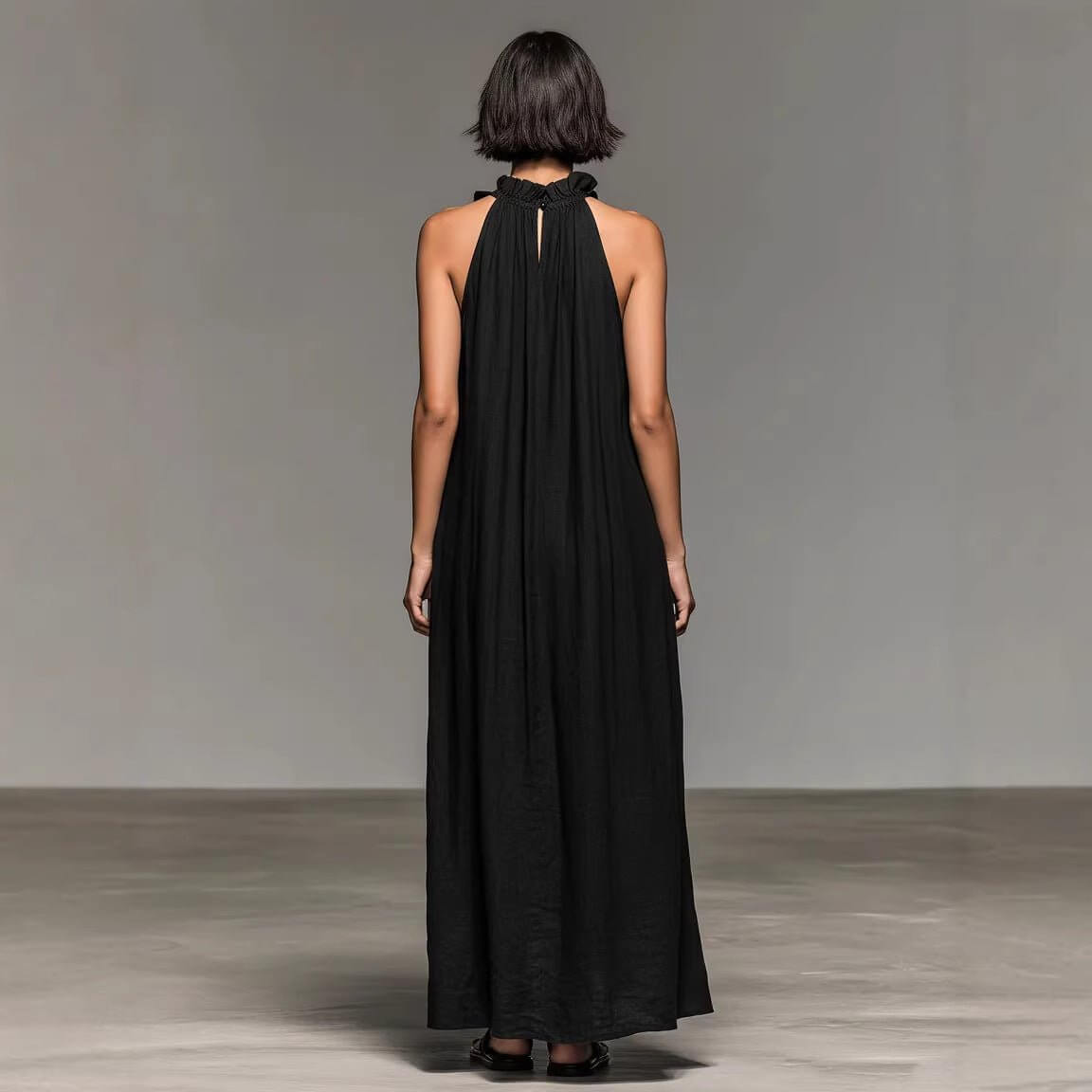 Back view of the black maxi dress featuring a ruffled neckline and loose fit, highlighting elegant design.