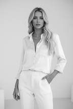 Lifestyle shot of a white satin long sleeve blouse featuring a v-neck, perfect for a refined capsule wardrobe.