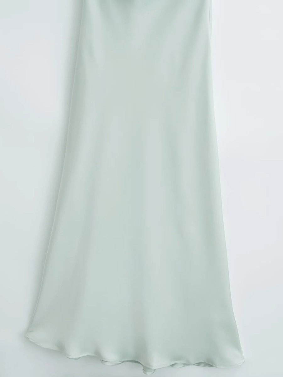Detail shot of the light green satin sling dress, showcasing its flowy hem and silk texture for a refined look.