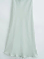 Detail shot of the light green satin sling dress, showcasing its flowy hem and silk texture for a refined look.