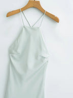 Detail view of the light green satin sling dress, highlighting its spaghetti straps and elegant silk texture.