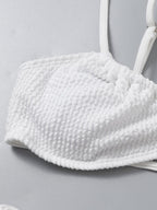 Detail close-up of a white bikini top highlighting padded cups and soft fabric, perfect for a minimalist swimwear collection.