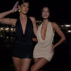 Side view of a black halter dress with a deep V-neck in a natural setting, showcasing its minimalist appeal.