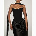 Detail close-up of the black off-shoulder dress, featuring a v-neck and elegant ribbon accents.