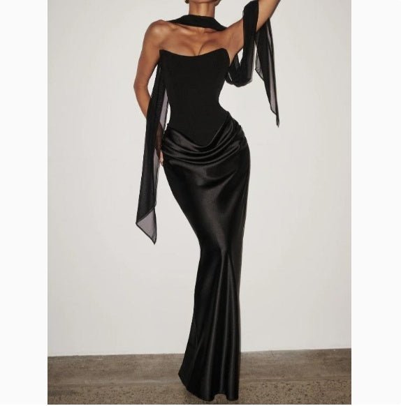 Back view of the black off-shoulder dress, highlighting its figure-hugging silhouette and ribbon details.