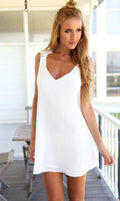 Flowy white beach cover-up with v-neck and sleeveless design, stylish minimalist outfit in a lifestyle setting.