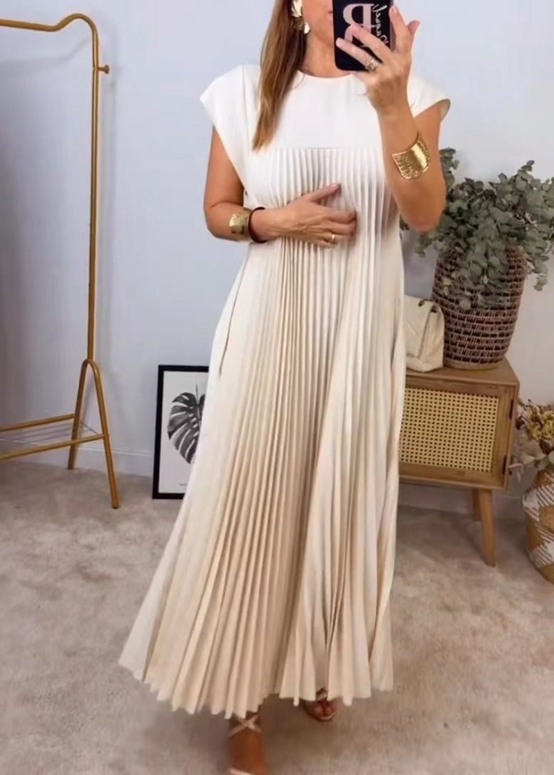 Elegant beige pleated long dress with flowing skirt, emphasized in a natural environment.